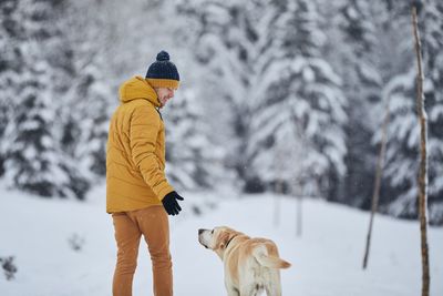 Man with dog standing on snowy land