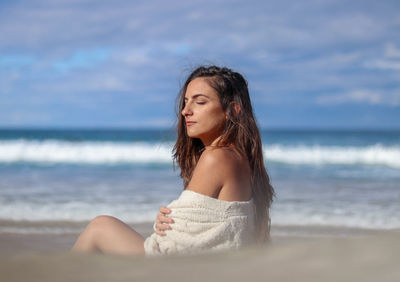 Portrait of young woman standing at beach