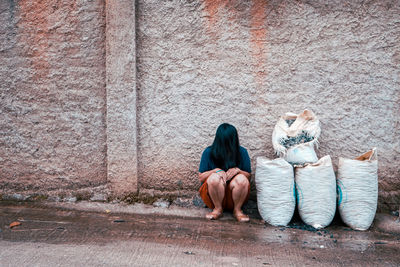 Rear view of woman sitting on footpath