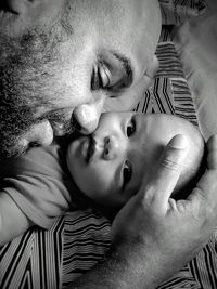 Close-up of father loving son lying on bed