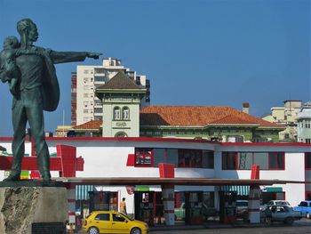 Statue in city against clear sky