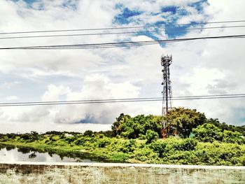 Low angle view of electricity pylon against cloudy sky