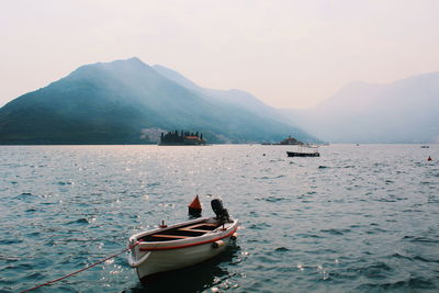 Boat moored on sea against mountains