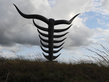 Metallic structure on field against sky