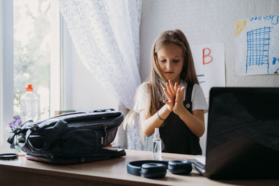 Cute girl using hand sanitizer at home