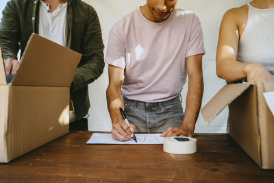 Male volunteer making name tag while standing with colleagues near table at community center