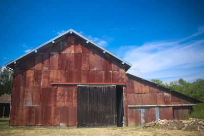 Old barn on field against blue sky