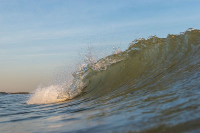 Waves splashing on shore against sky