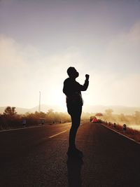 Full length of silhouette woman standing on road against sky
