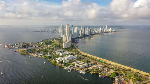 High angle view of city by sea against sky