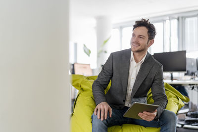 Young man using smart phone while sitting on laptop