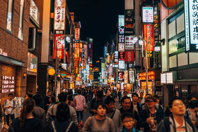 People on illuminated street in city at night