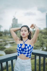 Portrait of young woman standing against sky