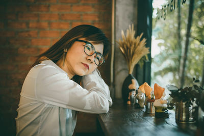 Side view of thoughtful young woman looking away by window