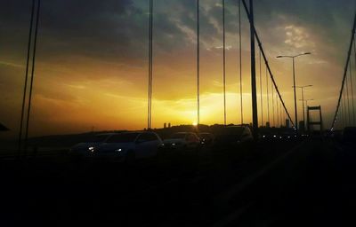 Cars on road against dramatic sky during sunset