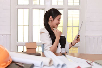 Young woman looking at camera while sitting on table