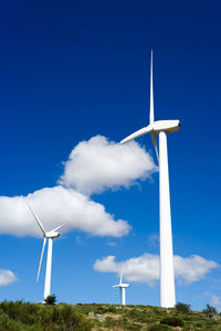 Low angle view of windmill on field against blue sky