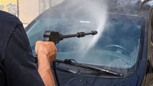 Man spraying water on car windshield