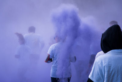 People amidst purple powder paint during holi