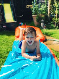 Portrait of boy on water slide at backyard