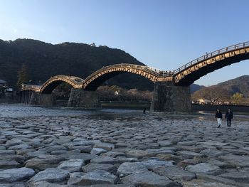 Arch bridge over rocks against sky