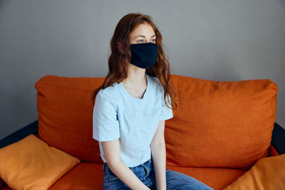 Young woman wearing sunglasses while sitting on sofa at home