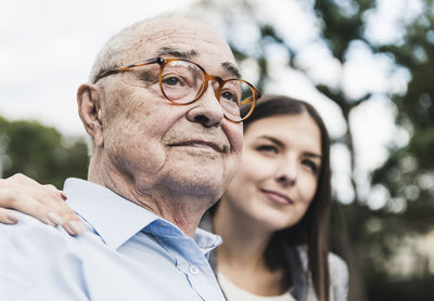 Portrait of self-confident senior man with granddaughter in the background