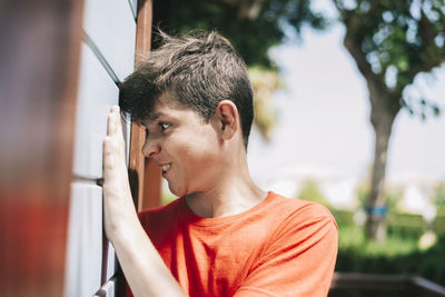 Teenage boy standing outside house