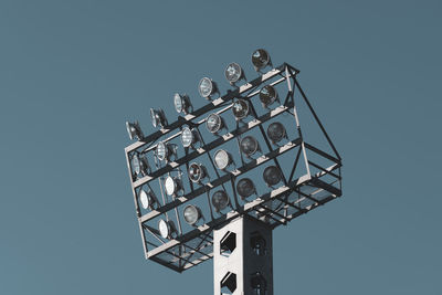 Low angle view of floodlights against clear blue sky