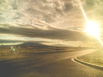 Road in city against sky during sunset