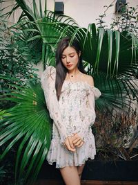 Portrait of young woman standing against plants