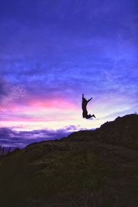 Silhouette of woman jumping against sky