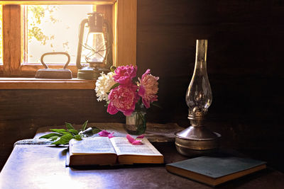 Still life of vintage items and a bouquet of peonies on a table by the window in an  village house