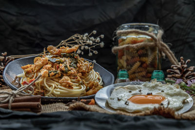 Spaghetti by fried egg in plate on table