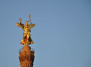 Low angle view of angel statue against clear blue sky