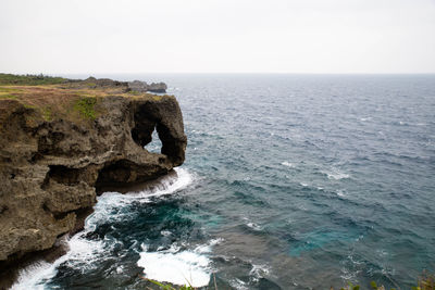 Rock formation in sea against clear sky
