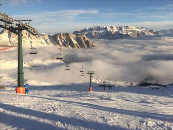 Scenic view of snow covered mountains and calley filled with low clouds against sky