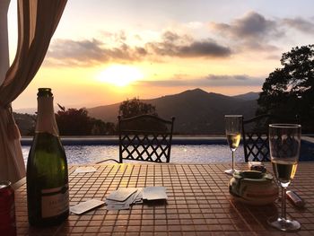 Chairs and tables on table against sky during sunset