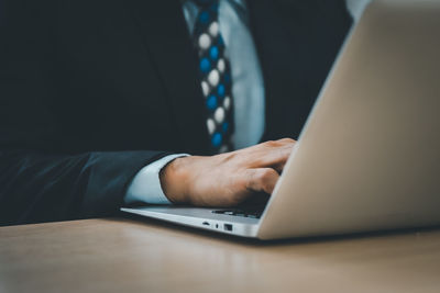 Midsection of man using laptop on table