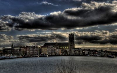 City at waterfront against cloudy sky