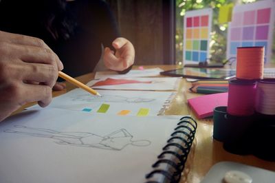 Cropped image of fashion designers drawing on paper