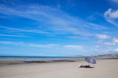 Man sitting on beach against sky