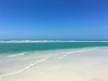 Scenic view of beach against clear blue sky