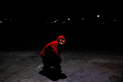 Full length portrait of man standing on street at night