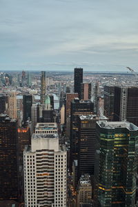 Aerial view of city buildings against cloudy sky