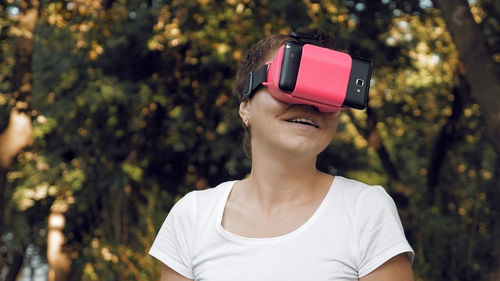 Woman using virtual reality simulator against trees