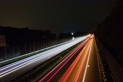 Light trails on road against sky at night