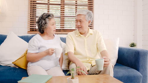 Couple holding hands while sitting on sofa at table