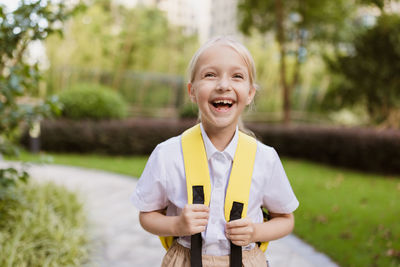 Back to school. little girl with yellow backpack from elementary school outdoor