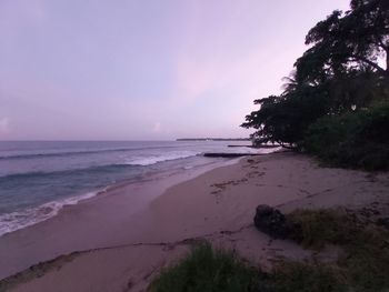 Scenic view of beach against sky at sunset